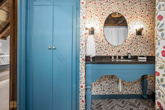 ensuite bathroom with wallpapered walls, vanity, brick floor, and ensuite bathroom