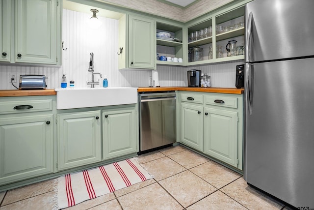 kitchen featuring a sink, appliances with stainless steel finishes, green cabinets, and light tile patterned floors