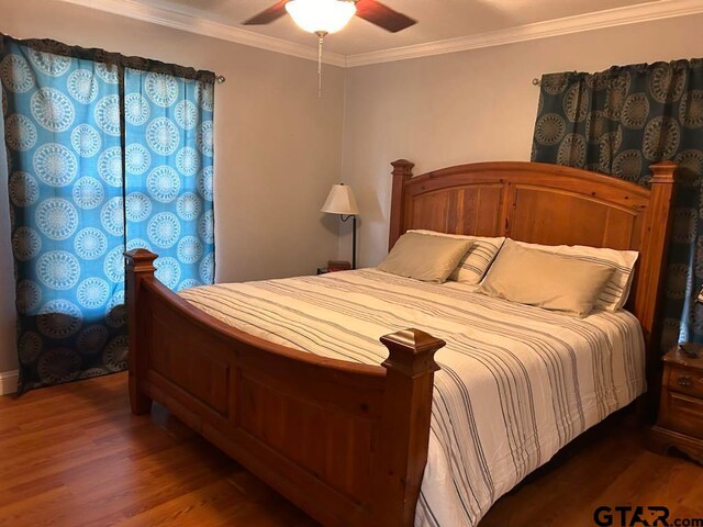 bedroom with dark wood-type flooring, ceiling fan, and crown molding