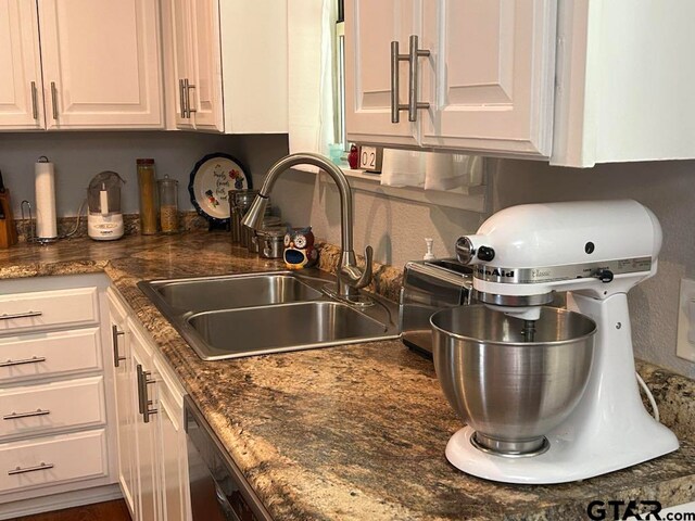 kitchen featuring dark stone countertops, white cabinetry, sink, and dishwasher