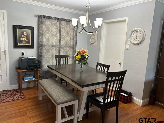 dining area with hardwood / wood-style flooring, a notable chandelier, and ornamental molding