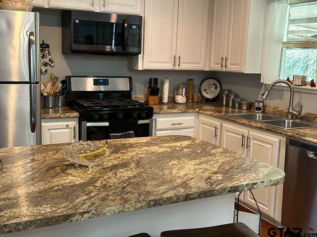 kitchen with white cabinetry, sink, a breakfast bar, and stainless steel appliances