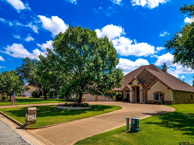 view of front facade with stone siding, a front lawn, and driveway