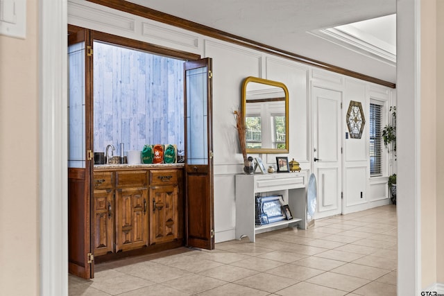 tiled entrance foyer featuring sink and ornamental molding