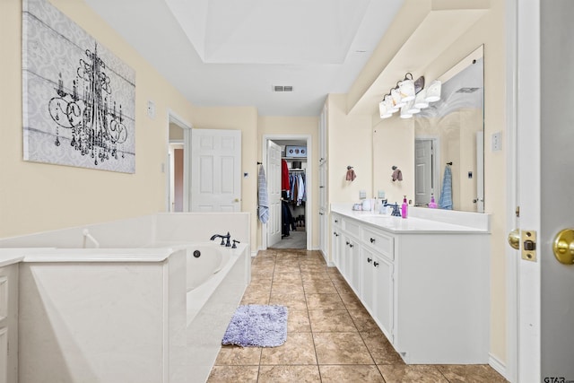 bathroom featuring tiled tub, tile patterned flooring, and vanity