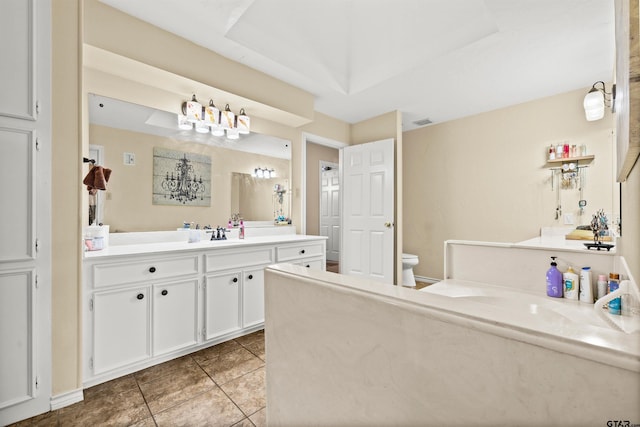 bathroom featuring tile patterned floors, vanity, a tray ceiling, and toilet