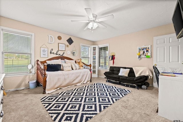 carpeted bedroom featuring multiple windows and ceiling fan