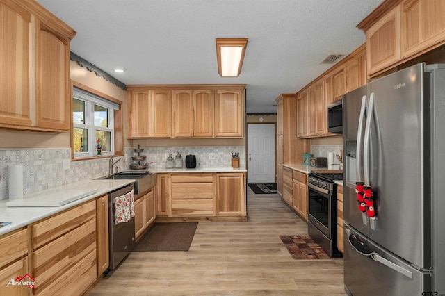 kitchen with stainless steel appliances, light countertops, visible vents, and light wood-style flooring