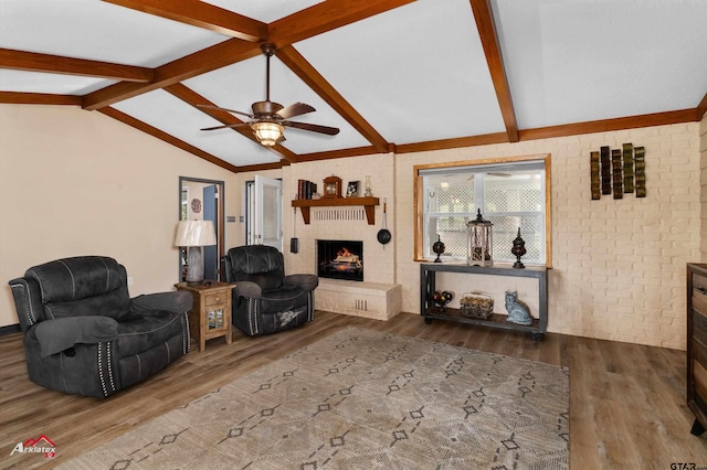 living room with lofted ceiling with beams, brick wall, a brick fireplace, and wood finished floors