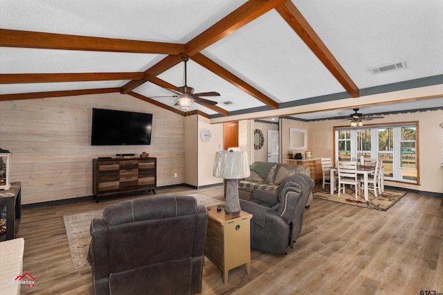 living room featuring vaulted ceiling with beams, wood finished floors, visible vents, and a ceiling fan