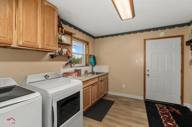 clothes washing area featuring baseboards, light wood-type flooring, cabinet space, and washer and dryer