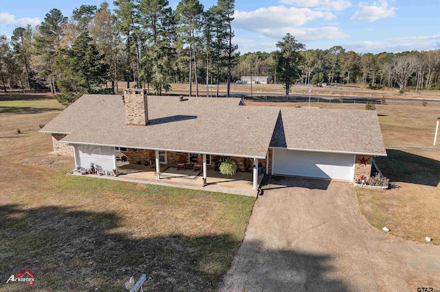 view of front facade with a shingled roof, a patio, and a front lawn