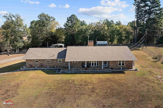 view of front facade featuring a patio, a chimney, roof with shingles, fence, and a front lawn