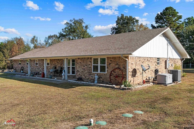 ranch-style house with a front lawn, roof with shingles, cooling unit, and brick siding