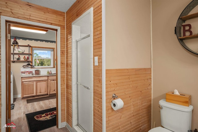 full bath with a stall shower, wooden walls, toilet, and wood finished floors