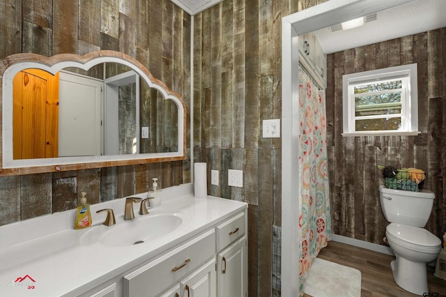 full bathroom featuring wood finished floors, wood walls, vanity, and toilet