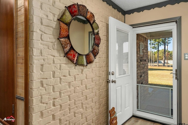 doorway to outside featuring brick wall and wood finished floors