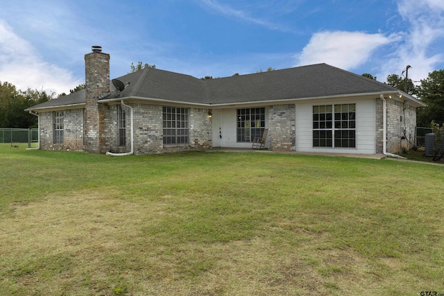 rear view of property with a yard and central AC