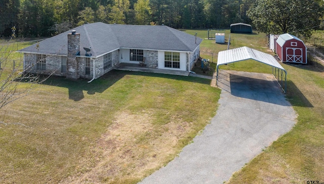 view of front facade featuring a carport, a storage unit, and a front yard