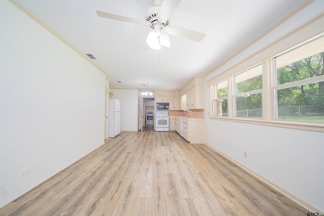 2504 Pounds Ave, Tyler, TX 75701 - unfurnished living room with brick wall, a chandelier, light wood finished floors, a ceiling fan, and baseboards