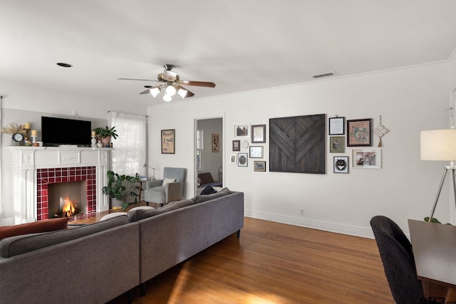 living room with dark hardwood / wood-style flooring, a tile fireplace, and ceiling fan