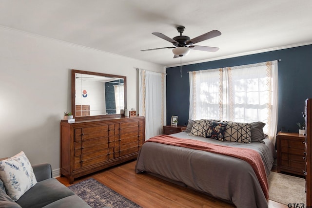 bedroom with ornamental molding, ceiling fan, and light wood-type flooring