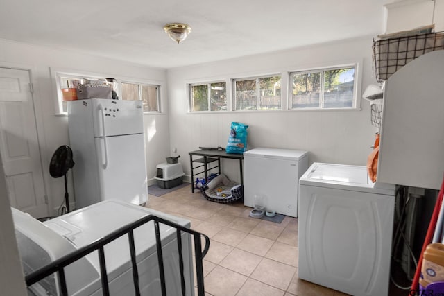 clothes washing area with light tile patterned flooring, a healthy amount of sunlight, and separate washer and dryer