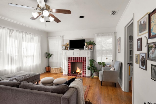 living room with a tiled fireplace, hardwood / wood-style flooring, and ceiling fan