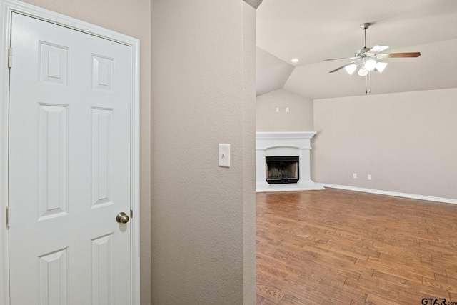 unfurnished living room with lofted ceiling, wood-type flooring, and ceiling fan