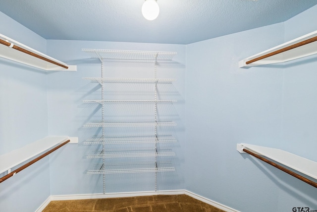 walk in closet featuring dark colored carpet