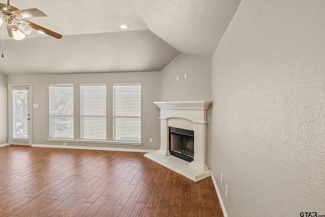 unfurnished living room featuring lofted ceiling, a textured ceiling, hardwood / wood-style flooring, and ceiling fan