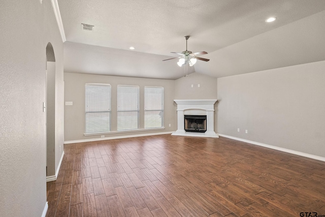 unfurnished living room featuring dark wood-type flooring, lofted ceiling, a textured ceiling, and ceiling fan