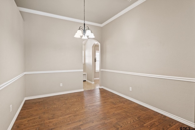 spare room with a chandelier, hardwood / wood-style flooring, and crown molding