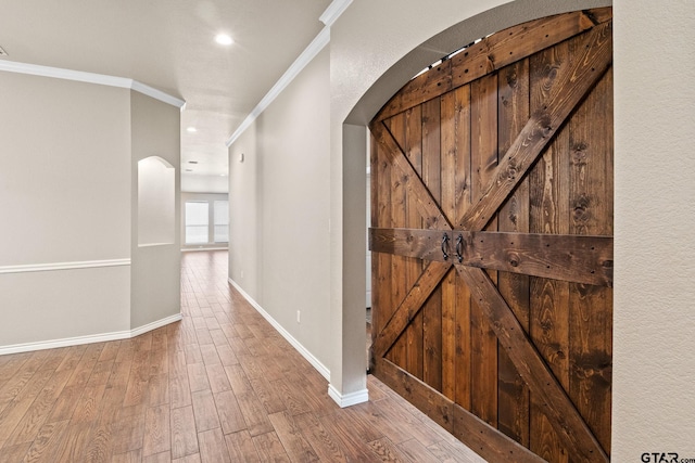 corridor featuring hardwood / wood-style floors, a barn door, and crown molding