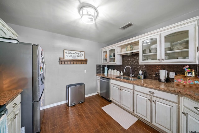 kitchen featuring appliances with stainless steel finishes, a sink, tasteful backsplash, visible vents, and glass insert cabinets