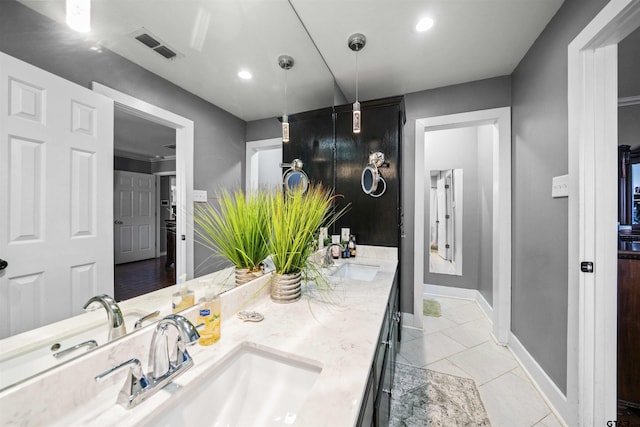 bathroom featuring a sink, baseboards, double vanity, and visible vents