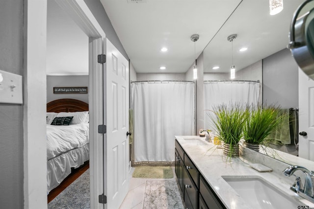 full bath with a sink, double vanity, recessed lighting, and ensuite bath