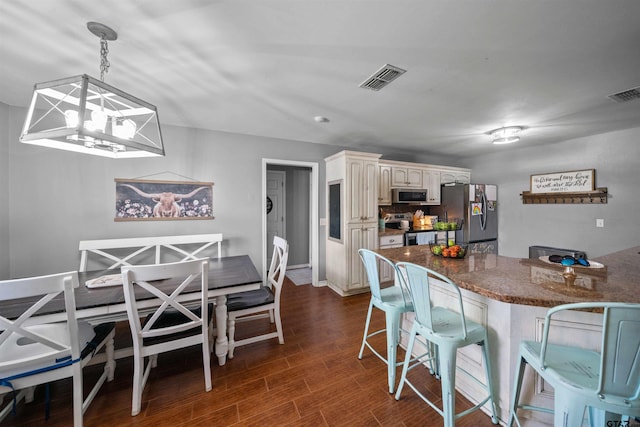 kitchen with visible vents, a kitchen breakfast bar, dark wood-style floors, and stainless steel appliances
