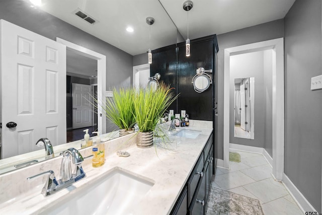 bathroom with baseboards, a sink, visible vents, and double vanity