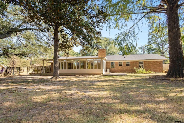 back of property with a lawn and a sunroom