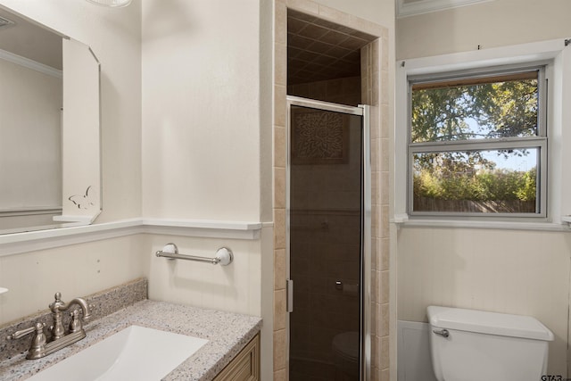 bathroom featuring ornamental molding, vanity, toilet, and a shower with door