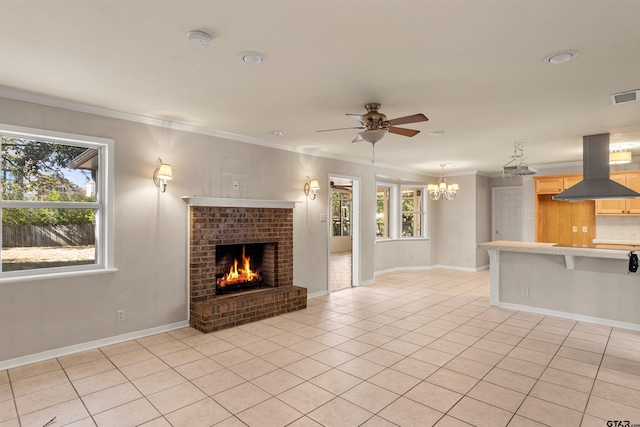 unfurnished living room featuring a brick fireplace, ceiling fan with notable chandelier, light tile patterned floors, and crown molding