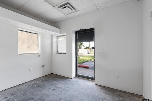 spare room featuring a paneled ceiling and concrete floors