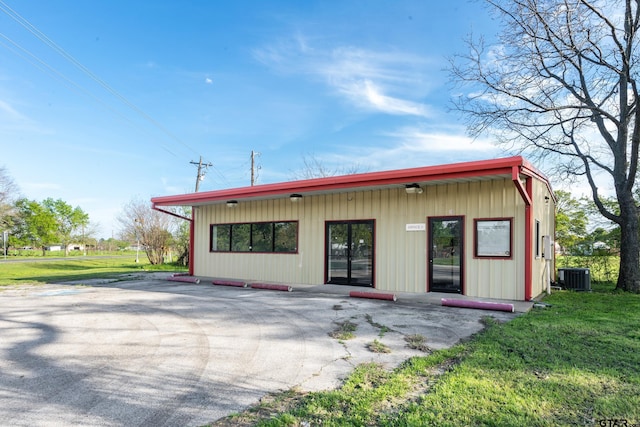 view of front of property featuring a front yard, central AC unit, and a patio