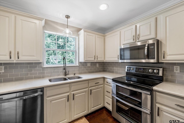 kitchen featuring a sink, light countertops, appliances with stainless steel finishes, hanging light fixtures, and decorative backsplash