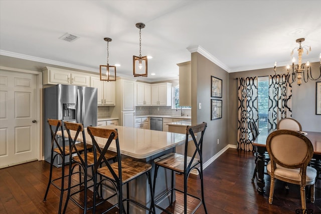 kitchen featuring dark wood-style floors, light countertops, visible vents, appliances with stainless steel finishes, and ornamental molding