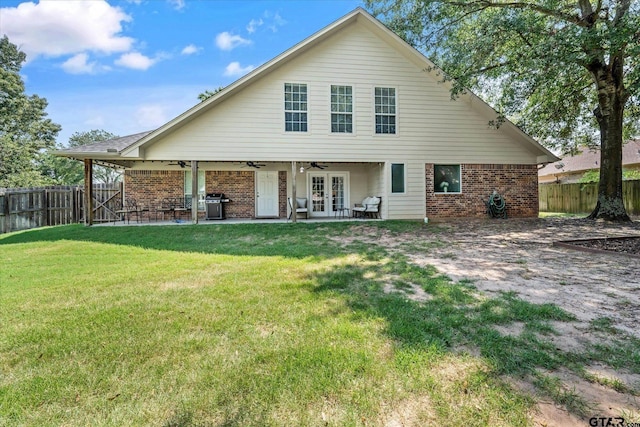 rear view of property with ceiling fan, a fenced backyard, brick siding, french doors, and a lawn