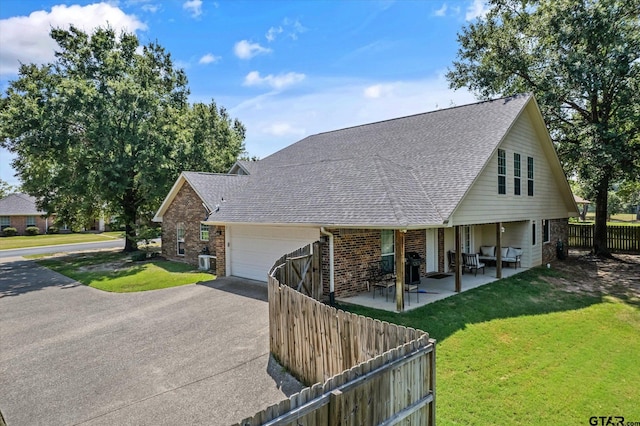 view of front of house featuring a garage, roof with shingles, fence, a front yard, and brick siding