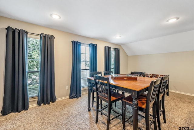 dining area featuring lofted ceiling, baseboards, and light colored carpet