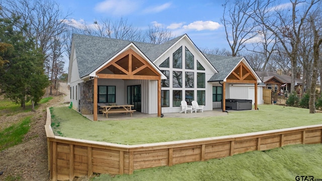 back of house featuring a hot tub, a lawn, and a patio area